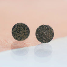 Load image into Gallery viewer, A pair of full moon stud earrings with ear sticks. Rough raw organic texture on flat round earrings. The silver is oxidised so the texture is accentuated in with black on the silver. handmade with a moonscape texture to resemble the surface of the moon. Made in Copenhagen by Scottish designer Caroline Cloughley. 