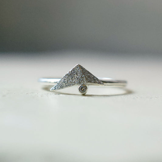 Beautiful unusual diamond ring. A folded silver triangle sits on top of a champagne diamond. The folded triangle is made in recycled sterling silver and has a rough, raw, rustic, organic texture. The ring has a delicate slim band. Handmade in Copenhagen by Scottish artist Caroline Cloughley.